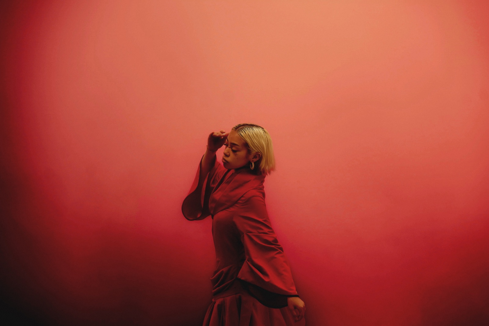 Ashalys contre un mur rouge, une main sur le front